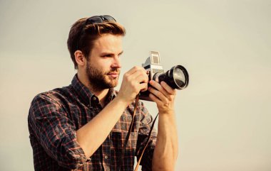 Adam açık havada gökyüzü arka planında. Fotomuhabir konsepti. Gezgin blogcu. Gazeteci fotoğraf çekiyor. Antika ekipmanlar. Blogger video blogu çekiyor. Tatil zamanı. Yakışıklı blogcu adam gezgin geçmişe dönük kamera