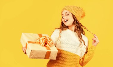 Alışveriş Merkezi. Noel hediyesi kutusu olan mutlu küçük bir kız. Çocuk hediye kutusunu sarı arka planda tutuyor. Mutlu Noeller ve yeni yıl. Elimde Noel hediyesi var. Noel konsepti