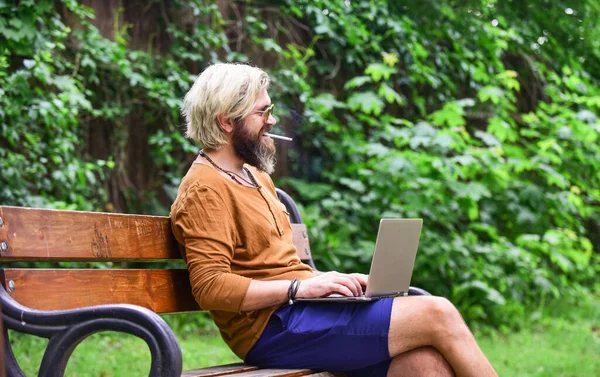 Parktaki bankta dizüstü bilgisayarlı bir iş adamı oturuyor. Laptopta çalışan yakışıklı adam. İş adamı dışarıda bilgisayarla çalışıyor. Video konferansına başla. Görüntülü arama ile iletişim. Bilgiye doğru — Stok fotoğraf