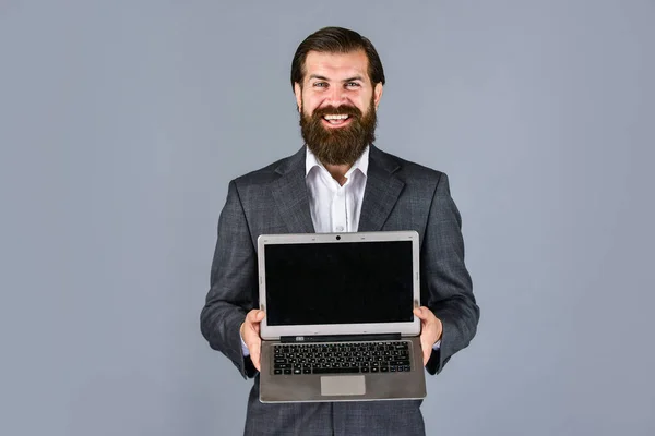 Självsäker affärsman med laptop. brutal man med skägg i kostym. Snygg VD som håller datorn. boss och anställd. agila affärer. online utbildningskoncept. handla på nätet — Stockfoto