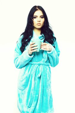 Turkuaz kadife bornozla fincanla poz veren seksi kız.