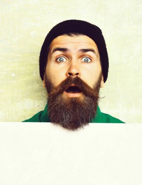 Stüdyo duvarında poz veren sakallı adam.