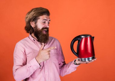 Buraya bak. Sakallı adam mağaza asistanı mutfak aletlerini sunar. Oda servisinde kullanışlı. Olgun karizmatik erkek elektrikli su ısıtıcısı kullanır. Sakallı ve bıyıklı adam çay yapıyor. Sıcak çay iç.