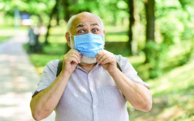 Virüsle savaşma stratejisi. Halka açık yerleri ziyaret etmek yasak. Maskeli kıdemli adam. Yaşlı adam parkta yürüyor. Coronavirus kapanışı sırasında hayat. Güzelliğin tadını çıkar. Hastalık korkusu. Keyfi yerinde.