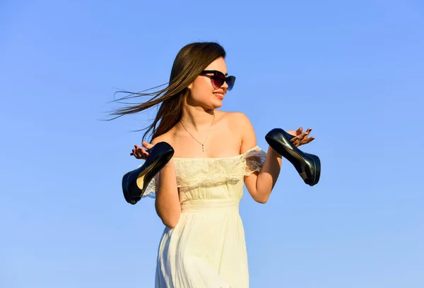 Свободу. Девушка в солнечных очках копирует пространство. Модель нежное летнее платье. Ближе к лету. Концепция афтерпати. Женщина-рассвет носит высокие каблуки в руке. Женщина на солнечном утреннем голубом небе. Летние каникулы — стоковое фото