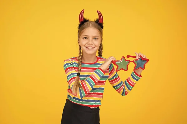 Deja que Halloween se llene de trucos con este accesorio. Los niños pequeños usan accesorios de disfraces de Halloween sobre fondo amarillo. Niña sostiene accesorio ojo de moda. Accesorio de fiesta para look Halloween — Foto de Stock