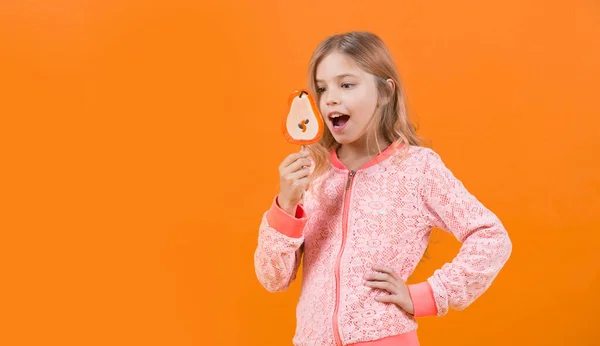 Mädchen lächeln mit Lutscher auf orangefarbenem Hintergrund — Stockfoto