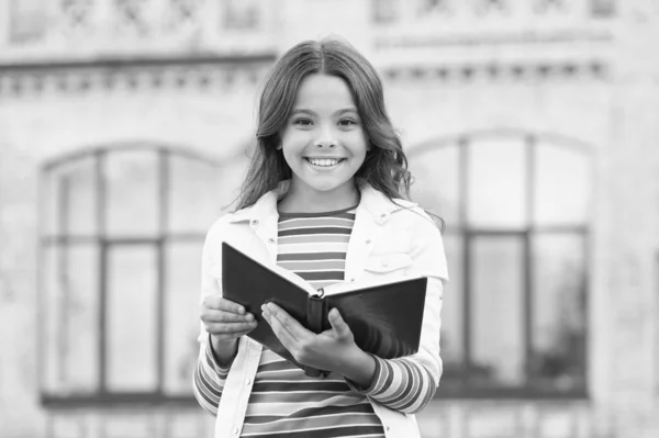 School library. Studying literature and language. Knowledge day. Inspiration concept. Bond over your favorite books and love of literature. Child hold library book outdoors. Little girl go to library