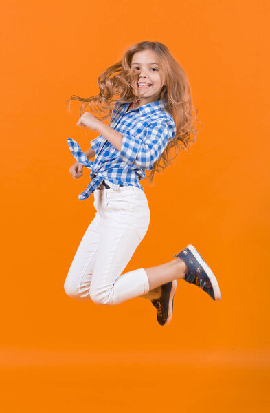 Child jump smiling on orange background