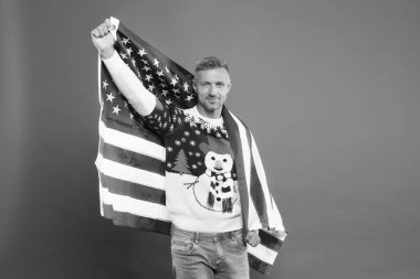 Anavatanım. Olgun adam Amerikan bayrağı taşıyor. Yakışıklı adam kış tatilini kırmızı arka planda kutluyor. Adam kışlık kazak giyiyor. Mutlu Noeller ve mutlu yıllar. En iyi dileklerimle. Kış tatili