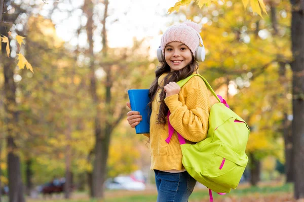 Школьница держит в руках книги и школьную сумку во время прогулки в парке — стоковое фото