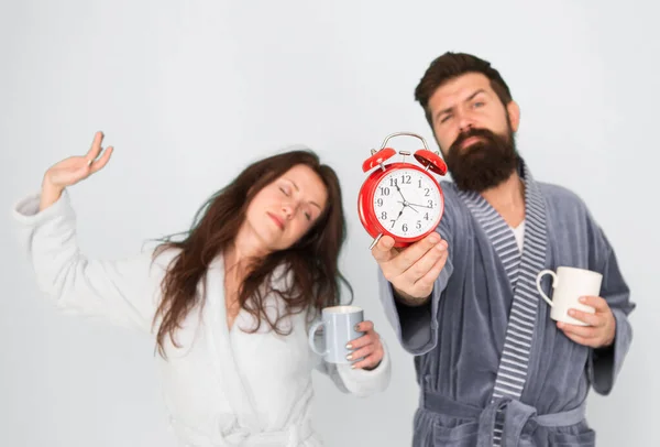 Hombre con barba y mujer somnolienta disfrutar de café o té por la mañana. El tipo con ropa de baño tiene café de té. Concepto de desayuno. Todas las mañanas comienza con café. Pareja en albornoces con tazas. Es la hora del café — Foto de Stock