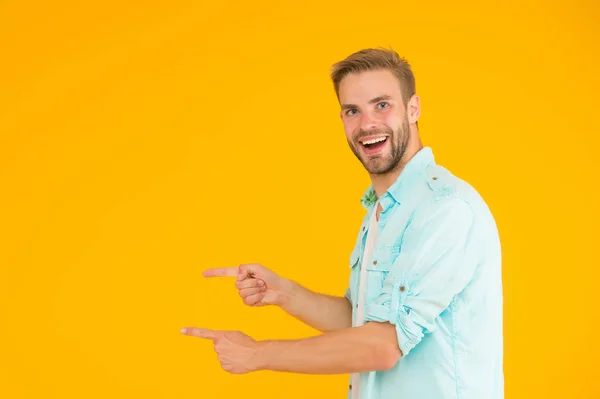 Fröhlicher Junge mit trendiger Frisur präsentiert Produkt. schöner unrasierter Mann mit borstigem Zeigefinger. Männer Sommer lässige Mode Stil. Glücklicher Kerl hat gepflegte Haare. Menschliche Emotionen. Kopierraum — Stockfoto