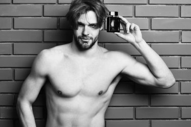 Beyaz sakallı seksi maço adam parfüm tutuyor.