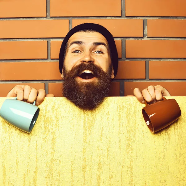 Barbudo brutal hipster caucásico con hoja de papel y tazas —  Fotos de Stock