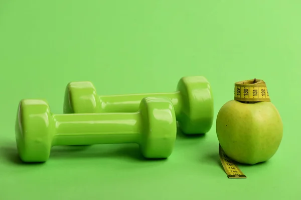 Haltères de couleur vert vif, ruban à mesurer et fruits — Photo