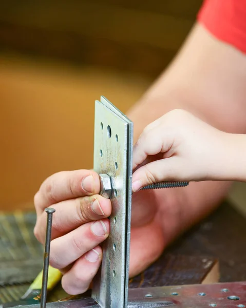 Mužské a dětské ruce spojující kovové desky, díly s šestihranným šroubem. Otec a syn opravují společně, zblízka. Childsova ruka pomáhá dospělým kroutit šroub. Koncept oprav a pomoci — Stock fotografie