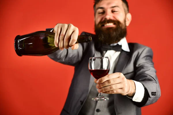 Homem com barba no fundo vermelho derrama vinho italiano — Fotografia de Stock