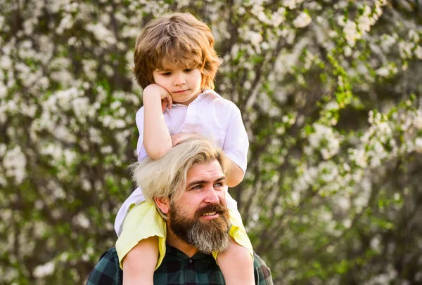 Lycklig familj. Pappadagen. Liten pojke och far i naturen bakgrund. Hipster och lille son i blommande trädgård. Skäggig brutal man, bra far. Pappa och son. Min lille son. Vårpromenad. Faderskap — Stockfoto