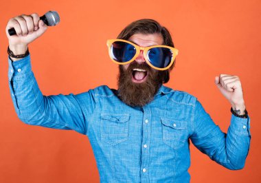 Çok duygusal. Yıldönümünü kutlamak. Partiye katılan. Sakallı hippi gözlüklü adam. Müzik konsepti. İyi tatiller. Partide iyi eğlenceler. Erkek şarkıcı mikrofonda şarkı söylüyor.