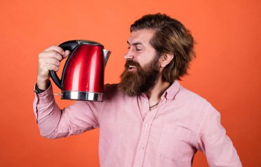 Bunu dene. Adam çay ya da kahve içecek. Bıyıklı ve sakallı vahşi bir adam. Elektrikli ev aleti. Sakallı adam kırmızı elektrikli su ısıtıcısı kullanıyor. Erkek ev idaresi konsepti. Sıcak suya ihtiyacım var.
