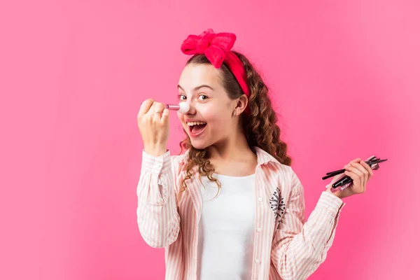 Blush ou sombras oculares. Tom perfeito. Salão de beleza. Moda adolescente. Aplicar cosméticos. Menina feliz com escovas de fixação de faixa de cabelo para maquiagem. Conceito de maquiagem. Cosméticos de pele jovem. Esconder imperfeições — Fotografia de Stock