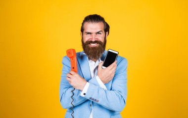 Sıradaki yeni. İki farklı telefon teknolojisi. Eski ve yeni. İletişim yöntemleri. Karşılaştırmalı teknoloji kavramı. Karşılaştırma. Adam eski telefonları ve akıllı telefonları karşılaştırıyor. Telefonun evrimi