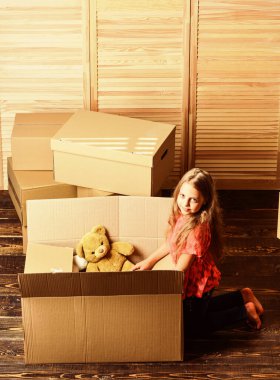 Mutlu bir çocukluk. Çocuklar için stresli bir ailenin yerini değiştirmek. Çocuk, arka plandaki kutuları değiştiriyor. Taşınma konsepti. Teslimat servisi. Kutu ve depo. Küçük çocuk taşınma için oyuncak hazırla