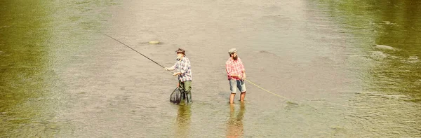 Summer weekend. Happy fisherman with fishing rod and net. Hobby and sport activity. Fishing together. Men stand in water. Fishing is much more than fish. Male friendship. Father and son fishing — Stock Photo, Image