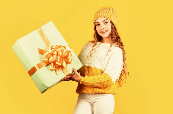 Feliz Año Nuevo para ti. Feliz navidad para ti. descuentos de vacaciones de invierno. niña alegre sombrero de punto y suéter. niño mantenga presente caja de fondo amarillo. Feliz año nuevo. regalo de Navidad venta de compras —  Fotos de Stock