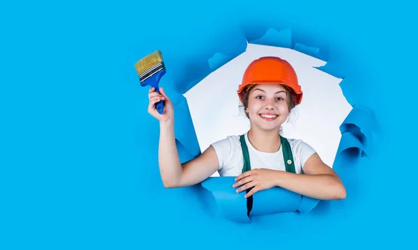 Ragazza in casco protettivo dipingere il muro. sviluppo dell'infanzia. Ragazzina costruttore. infanzia felice. Ragazza felice in casco di sicurezza tenendo pennello pittura. pronto a dipingere — Foto Stock