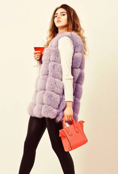 Elite fashion clothes. Designer clothing luxury fashion boutique. Woman with handbag hold glass of wine. Girl wear fashion fur vest while posing with bag. Luxury store concept. Lady likes shopping