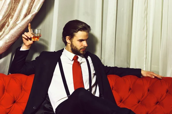 Бородатий чоловік, бізнесмен тримає келих віскі в червоній краватці — стокове фото