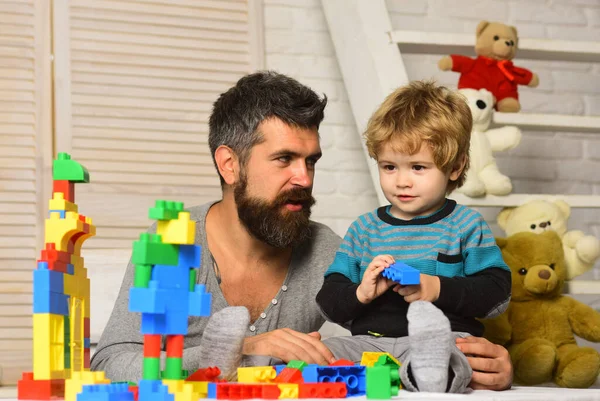 Pai e filho com rostos sorridentes criam construções coloridas — Fotografia de Stock