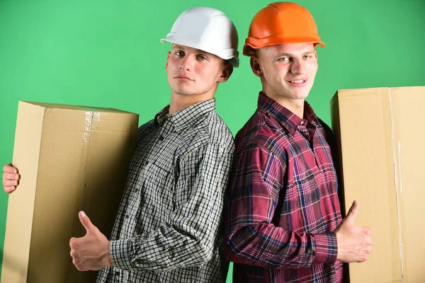 Mannen met zelfverzekerde gezichten houden kartonnen dozen op groene achtergrond — Stockfoto