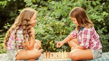 Spor ve hobi konsepti. Küçük kızlar satranç oynar. Satranç oynayan kız kardeşler. Bilişsel gelişim. Entelektüel oyun. Kararını ver. Akıllı çocuklar. Çocuklar açık havada satranç oynarlar.