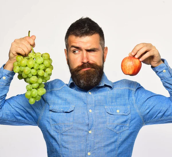 Vinodlare med klurigt ansikte håller druvor och röd frukt. — Stockfoto