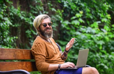 İstediğin yerde çalışabilirsin. Hippi parkta ilham kaynağı oldu. Çevik iş. Sakallı adam park doğasında bankta oturuyor. Çalış ve rahatla. Temiz hava. Gezici internet. İnternetten alışveriş. Çevrimiçi çalışma