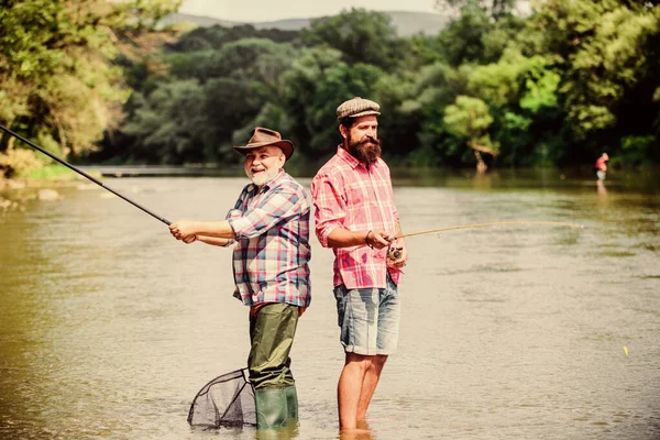 Hobby Matters. twee gelukkige visser met hengel en net. hobby en sport. Forel aas. mannelijke vriendschap. Familie binding. Zomers weekend. Volwassen visser. vader en zoon vissen — Stockfoto