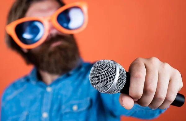 party goer. hipster man with beard wearing glasses. music concept. have a happy holiday. have fun on party. male singer singing song in microphone. selective focus. celebrate the anniversary