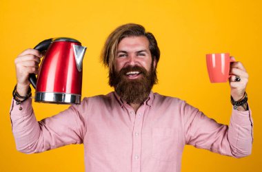 İyi günler dilerim. Sıcak çay iç. Sakallı adam mağaza asistanı mutfak aletlerini sunar. Oda servisinde kullanışlı. Olgun karizmatik erkek elektrikli su ısıtıcısı kullanır. Sakallı ve bıyıklı adam çay yapar.