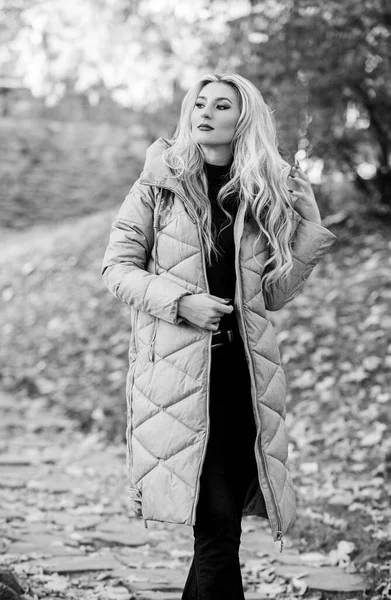 Divatos szőke lány sétál az őszi parkban. A nő meleg szürke kabátot visel. Mindenkinek kellett volna. Túlzott kabát trend. Hogyan rázzuk a golyóálló mellényt, mint a csillag. Puffer divat trend koncepció — Stock Fotó