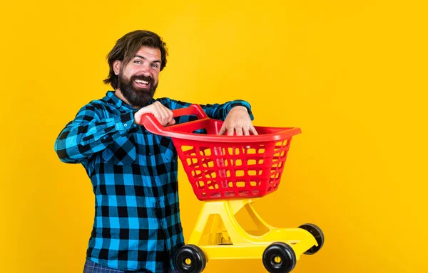 Glücklicher Mann mit Einkaufswagen über gelbem Hintergrund, Shopper im Geschäft — Stockfoto