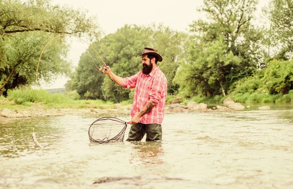 Fishing is astonishing accessible recreational outdoor sport. Bearded fisher catching trout fish with net. Fishing hobby. Fishing provides that connection with whole living world. Find peace of mind