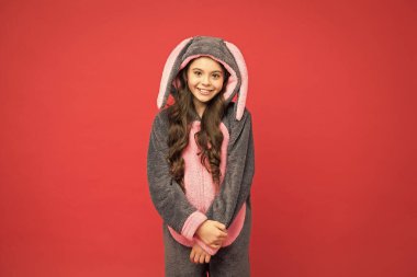 Tavşan pijamalı mutlu kız. Yaşam tarzı konsepti. Dinlen ve rahatla. Kırmızı arka planda sevimli tavşan çocuk. Bebek hayvan karakteri rolü. Sevimli tavşan. Tavşan kostümlü güzel kız. Tavşan kigurumideki çocuk