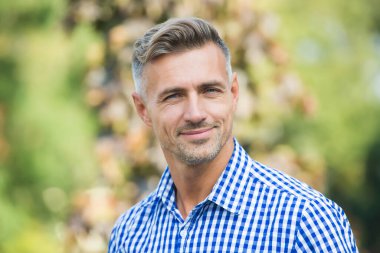 Pozitif insan duygularını ifade et. Olgun traşsız erkek gömleği. Erkek güz mevsimi modası. Dışarıda gülümseyen yakışıklı adam. Erkek saçı güzellik ve bakım. Berber salonu. yüz bakımı konsepti