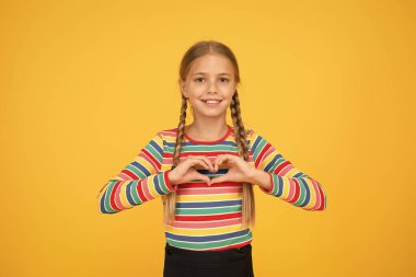 Sevgiyi paylaş. Sevimli kız güzel yüzü. Küçük kız. Sarı arka planda şirin örgülü saçı olan küçük bir çocuk. Çocuk bakımı konsepti. Genç kız rengarenk kıyafetler. Çocuk mağazası alışveriş merkezi