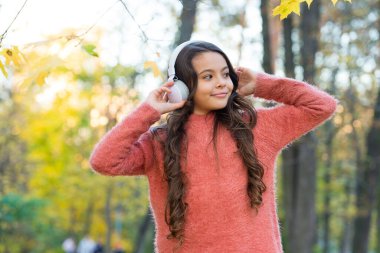 Çocuk sonbahar parkında müzik dinler. Sonbahar çalışma zamanıdır. Okula dönüyorum. Online eğitim kavramı. Kazaklı çocuk, dinleme kitabının keyfini çıkar. Yeni teknoloji. Kulaklıklı kız.