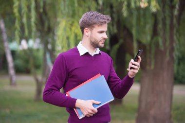 Telefonu elektronik kitapları ve teknolojiyi öğrenmek ve okumak için kullanan yakışıklı çocuk.