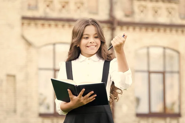 Vers la connaissance. La vie étudiante. Étudiant. Enfant intelligent. Tâche intellectuelle. Processus cognitif. Démarrer un nouveau projet scolaire. Bienvenue à l'école. École fille uniforme formel hold book — Photo